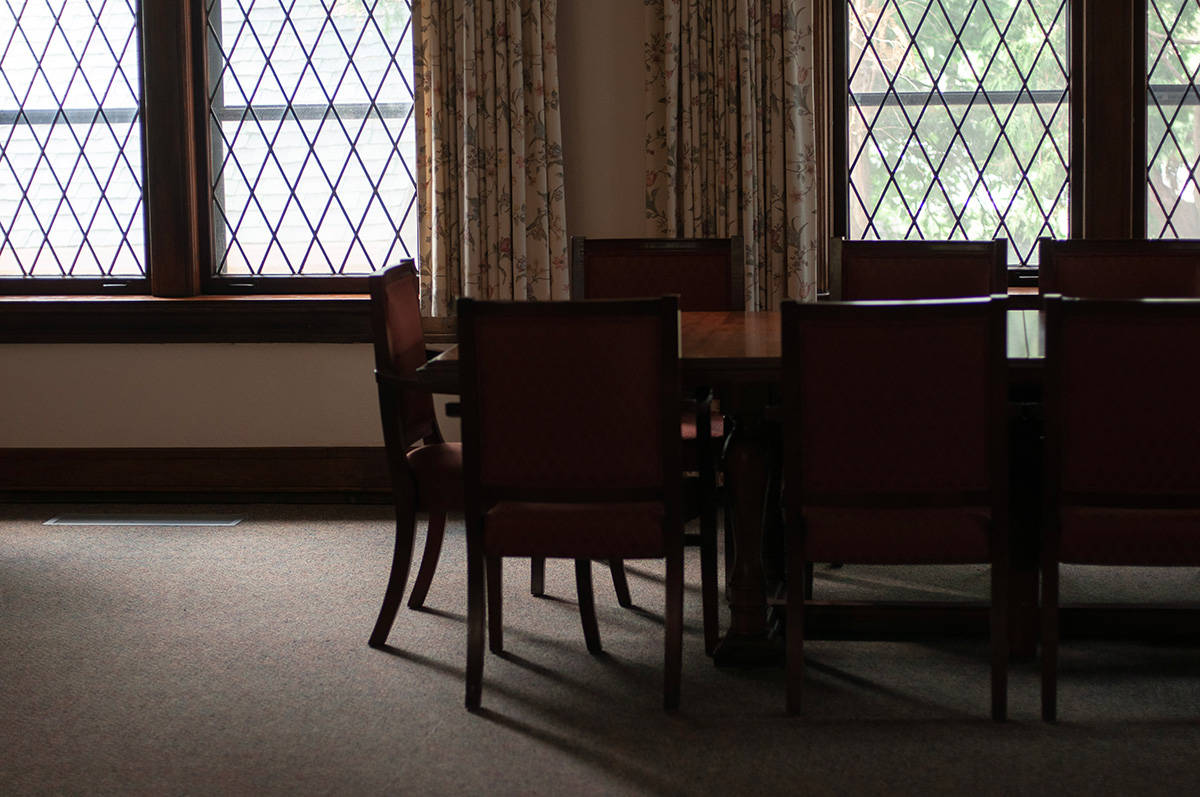 Large group table with chairs in front of windows in a dining hall at UU Wausau.