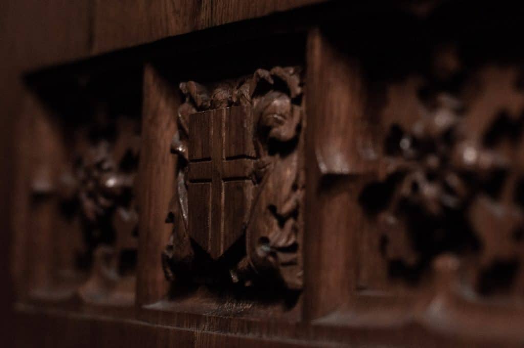 A wood pew with an intricately carved cross at the First Unitarian Universalist Church of Wausau.