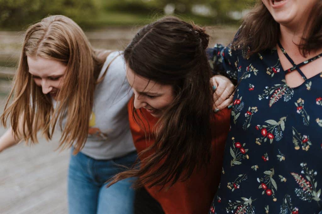 Three teen girls laughing together.