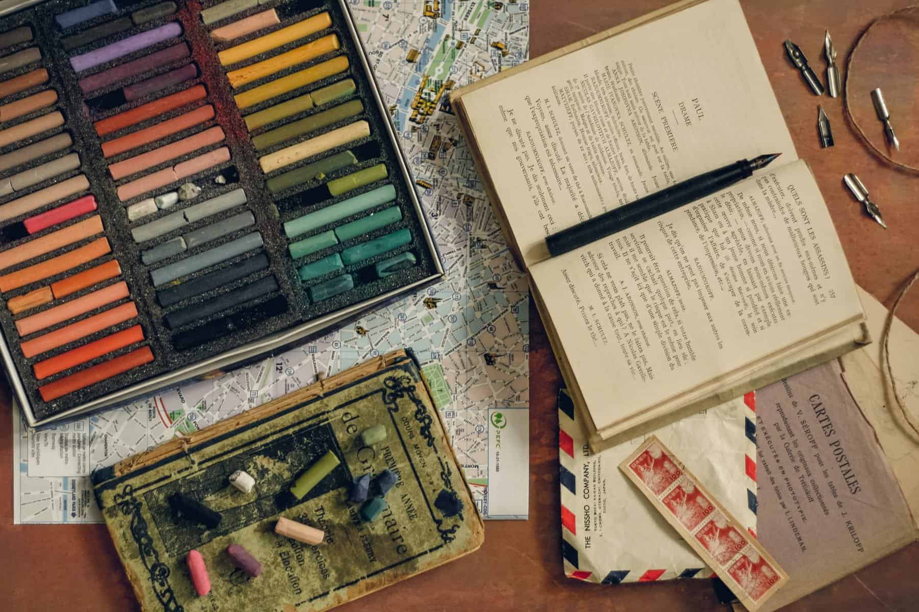 A collection of art supplies including a notebook and pastels.