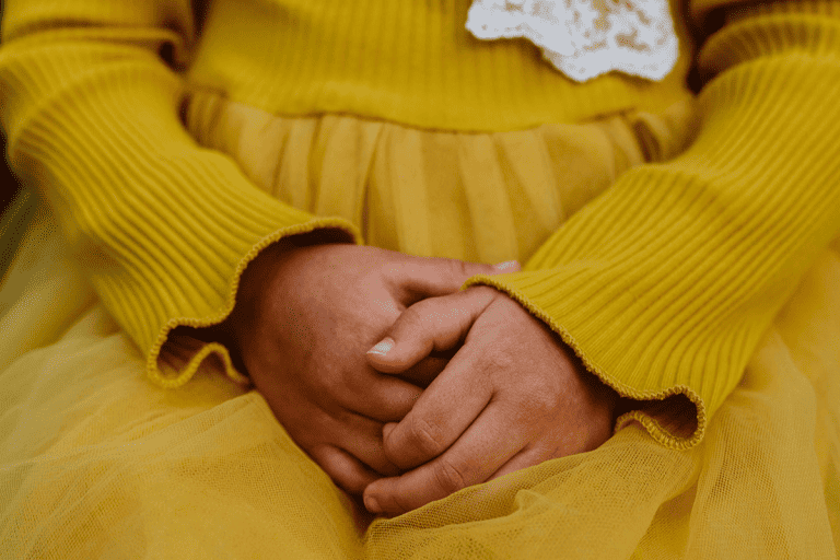 Young girl holding her hands together.