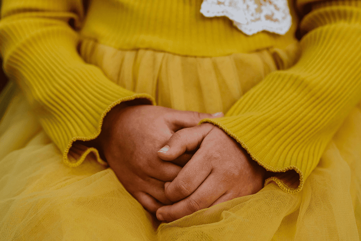 Young girl holding her hands together.
