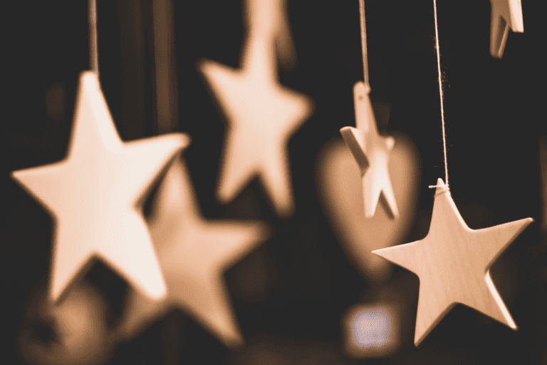 Floating gold stars hanging from strings on a dark background.