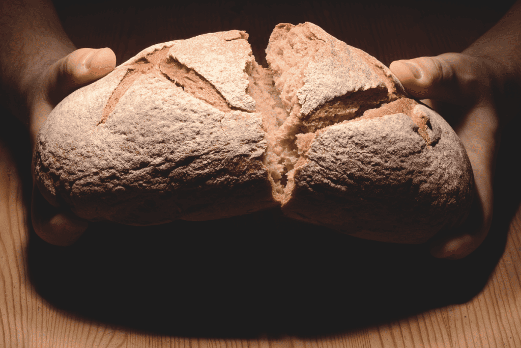 A man holding a French loaf of bread.